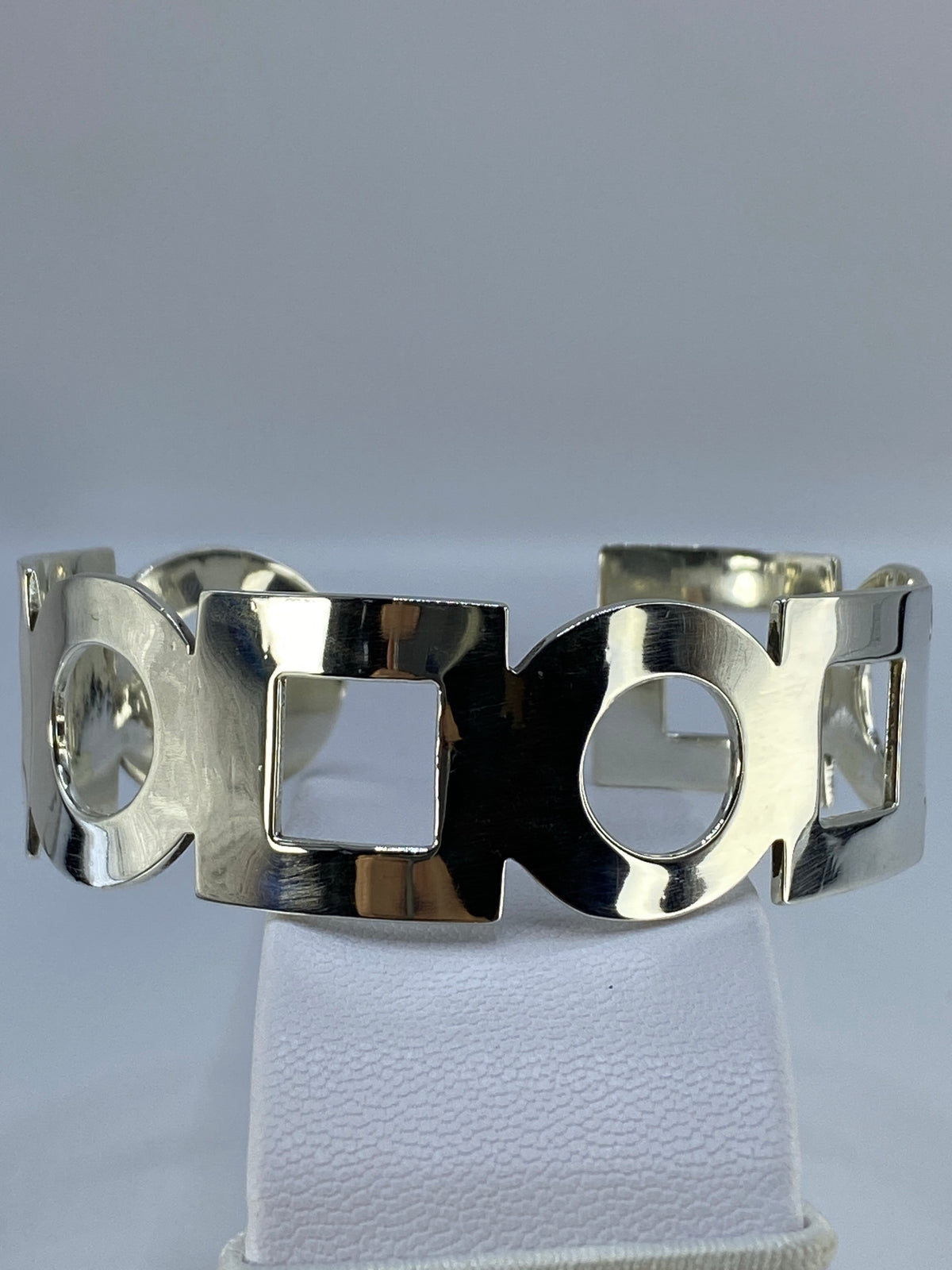 Brazalete de plata calado tipo esclava rígida visto de frente sobre fondo blanco