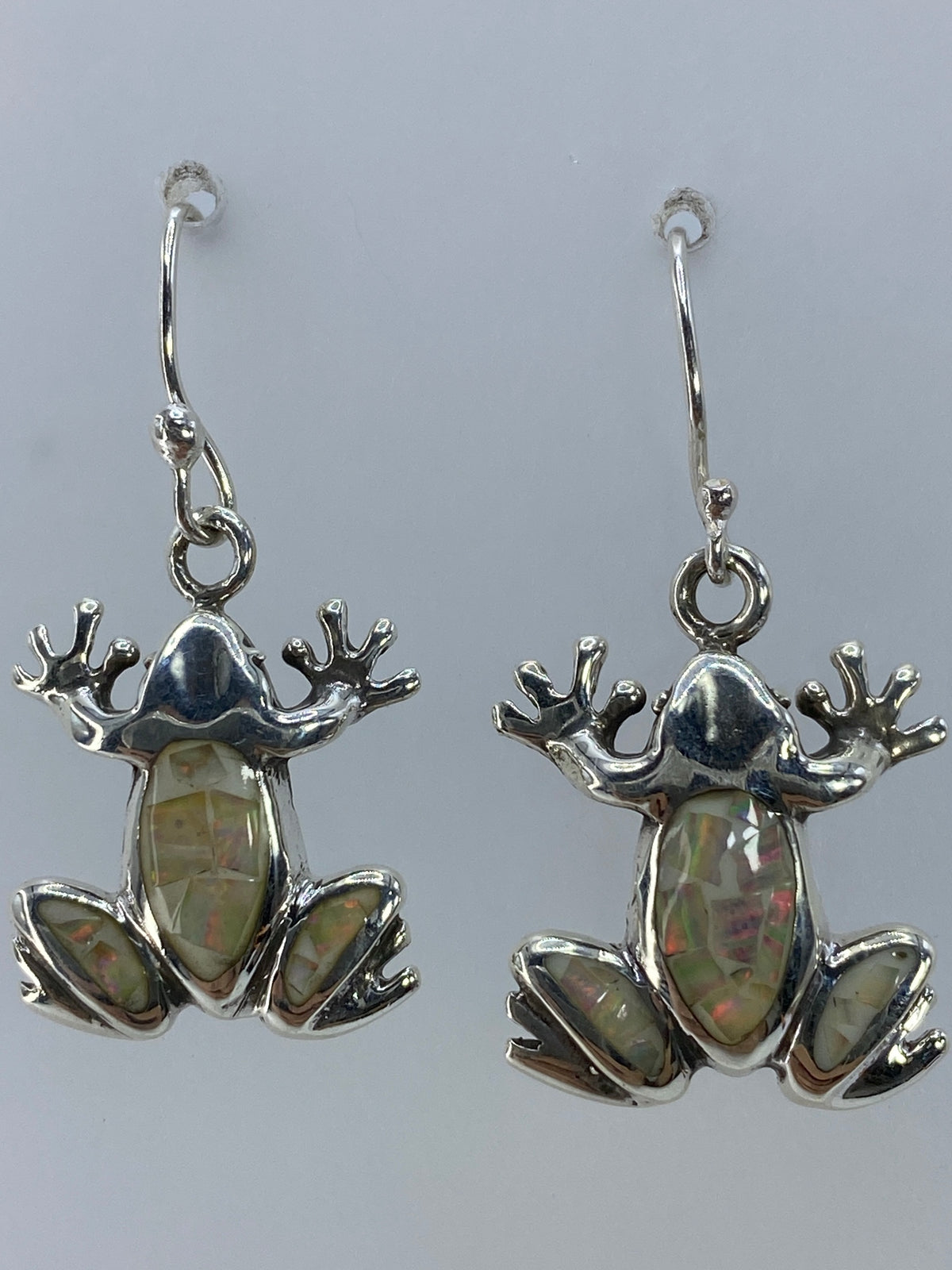 Aretes de sapo colgando de las orejas, mostrando el juego de luz del opalo