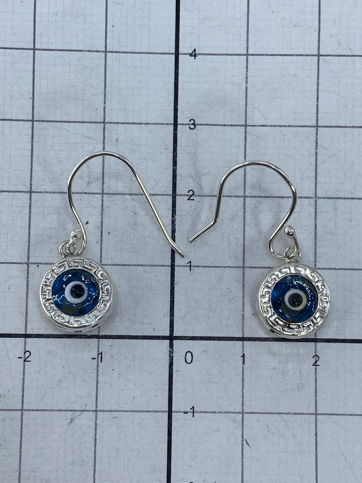 Aretes sobre tela azul destacando el brillo de la piedra azul cielo