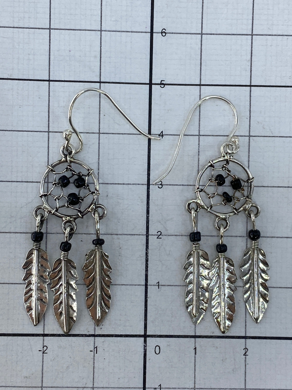 Aretes atrapasueños sobre fondo blanco mostrando el Quinto 925