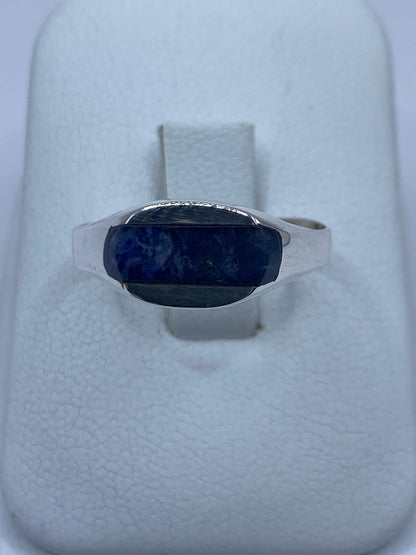 Anillo de plata con lapislázuli azul en la mano, mostrando el solitario engastado