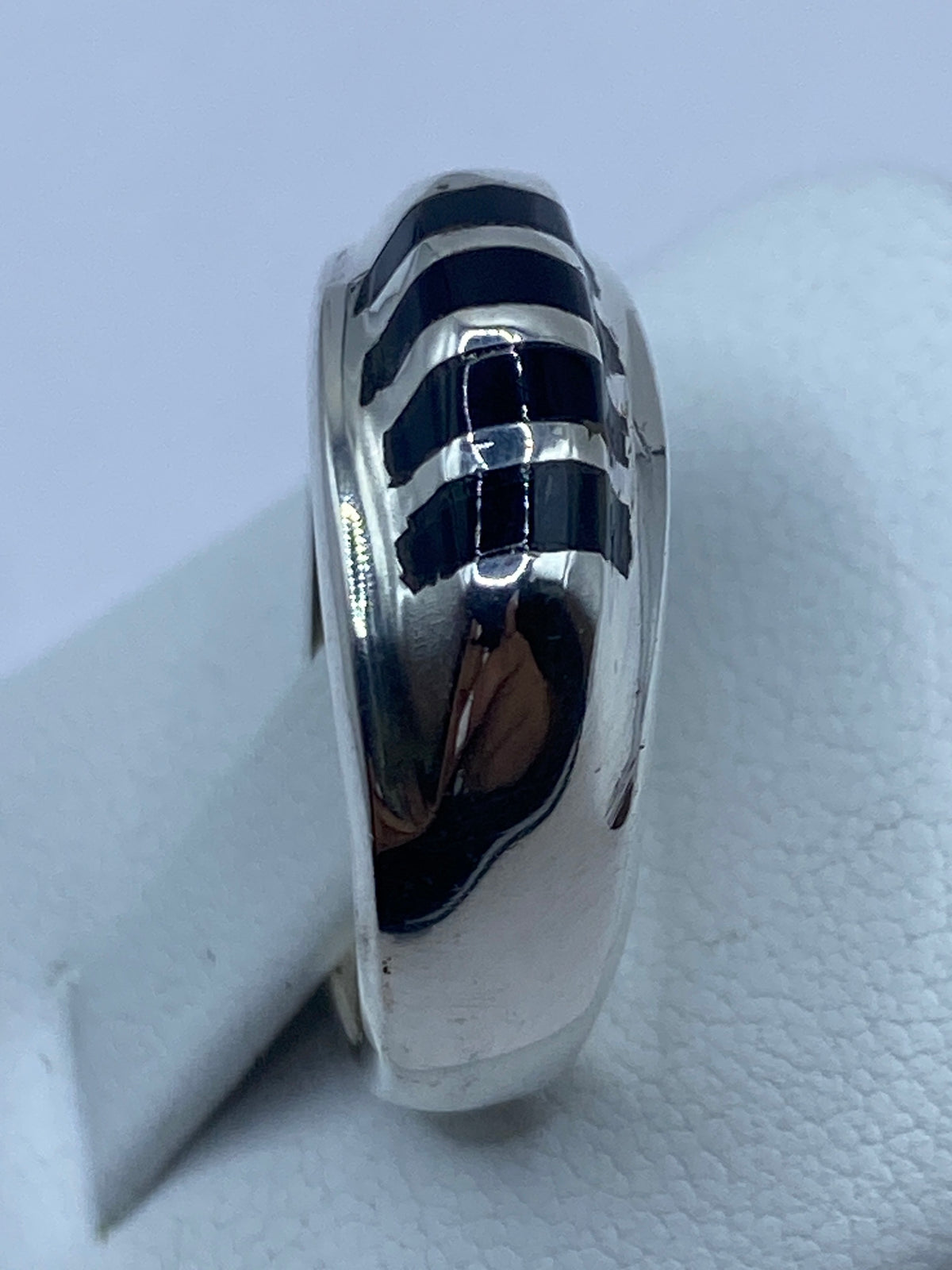 Anillo puesto en la mano, revelando el brillo profundo del ónix y el pulido de la plata