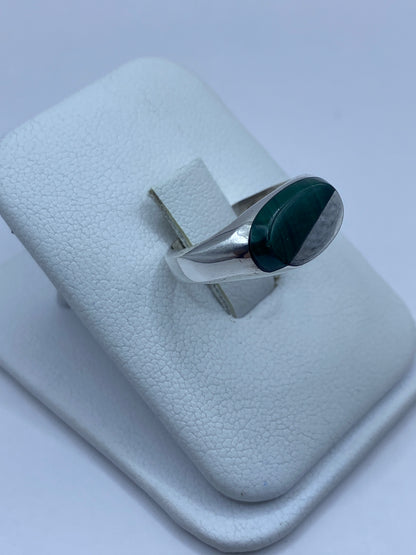Anillo en malaquita verde sobre dedo, mostrando el pulido de la plata y la piedra natural
