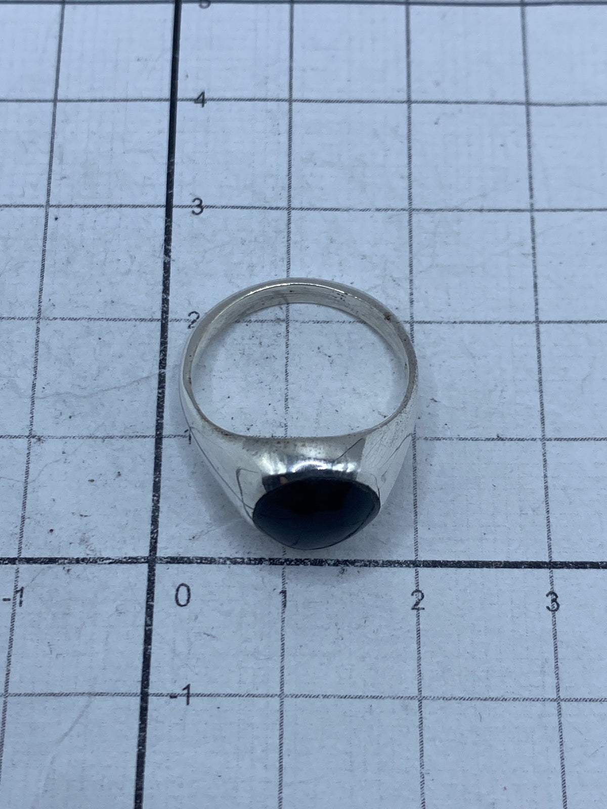 Anillo puesto en la mano mostrando el acabado pulido y el ónix negro brillante