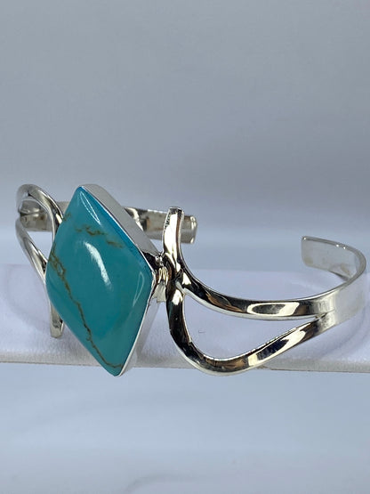 Brazalete de turquesa y plata puesto en la muñeca mostrando el color azul de la piedra