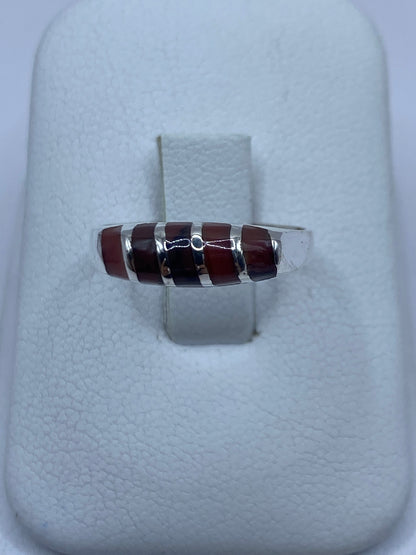 Anillo de plata 925 con piedra café engastada, visto de frente sobre estuche blanco