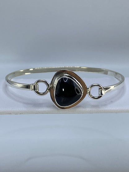 Brazalete de plata con ónix negro en muñeca de mujer