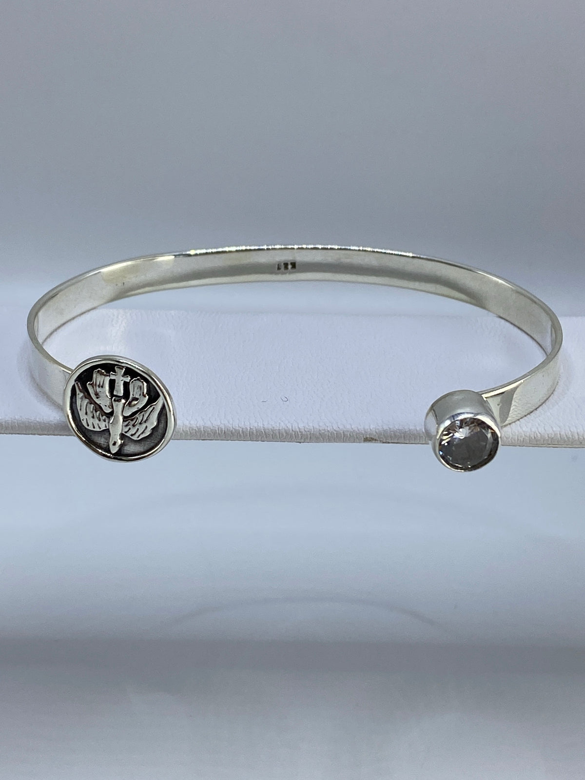 Brazalete de plata rígido con circonia cristalina, visto de frente en estuche