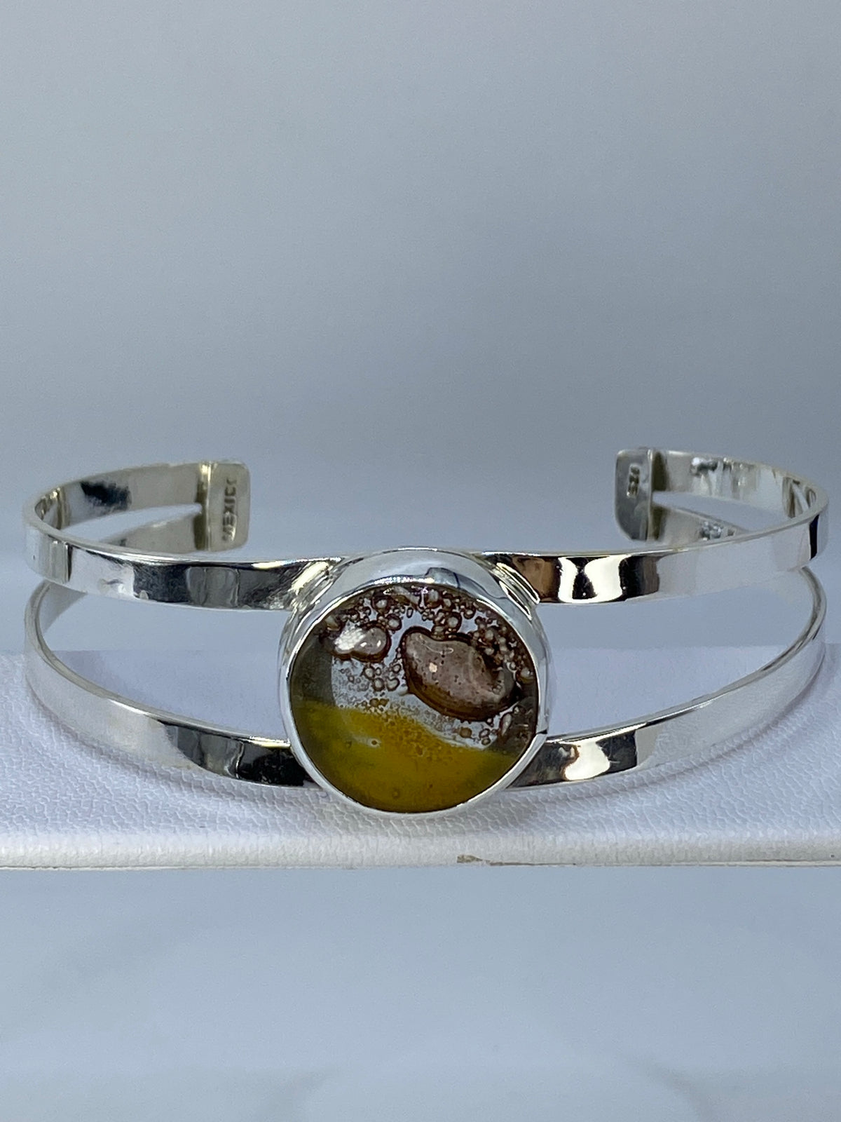 Brazalete rígido de plata 925 sobre fondo gris, vista frontal mostrando diámetro y ancho