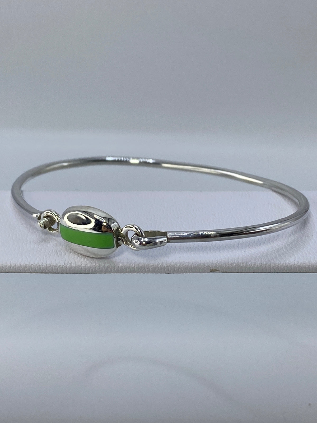 Vista lateral del brazalete de plata tipo puño sobre paño blanco