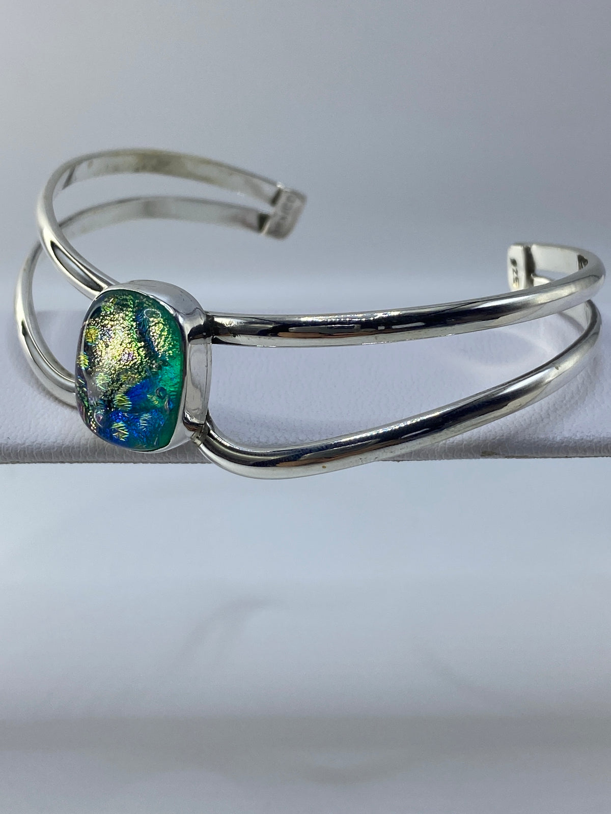 Brazalete de plata en forma de puño mostrando el ancho de 5 cm y la piedra multicolor