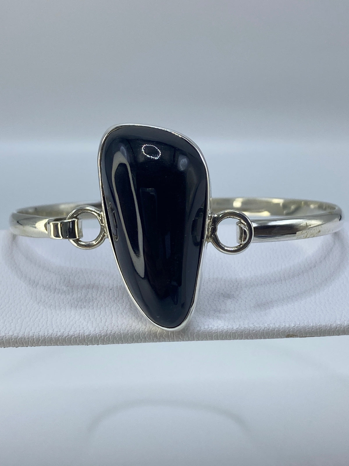 Brazalete rígido tipo esclava de plata pura con ónix brillante puesto en la muñeca