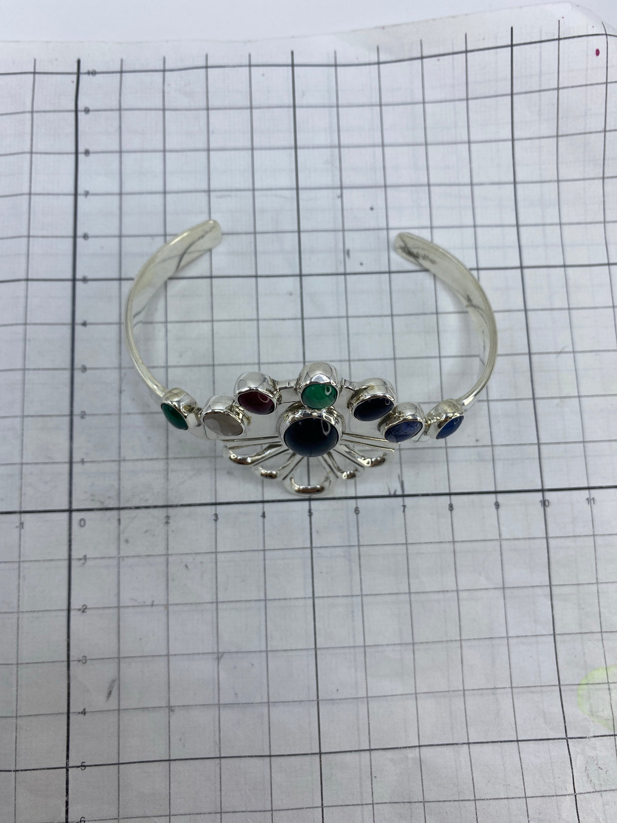 Brazalete puesto en la muñeca mostrando los pétalos calados y el peso de la plata