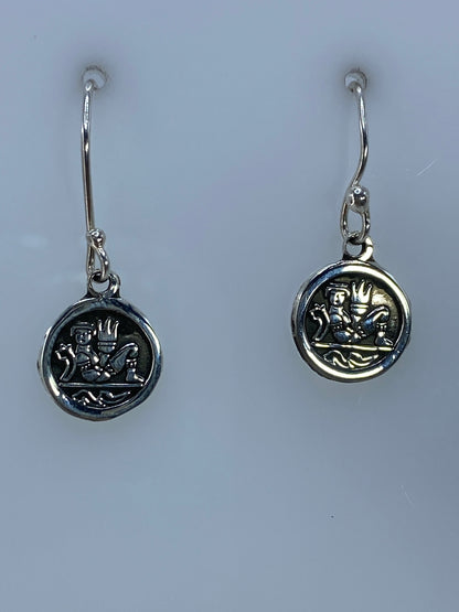 Par de aretes de plata en repujado con motivo prehispánico, vista frontal del diseño ritual