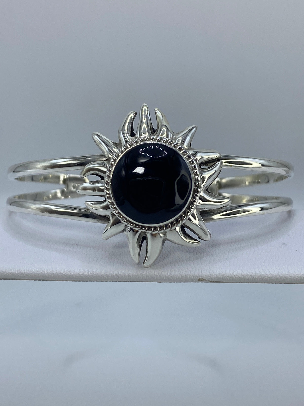 Brazalete de plata 925 rígido con ónix negro engastado, vista frontal mostrando el diseño de sol