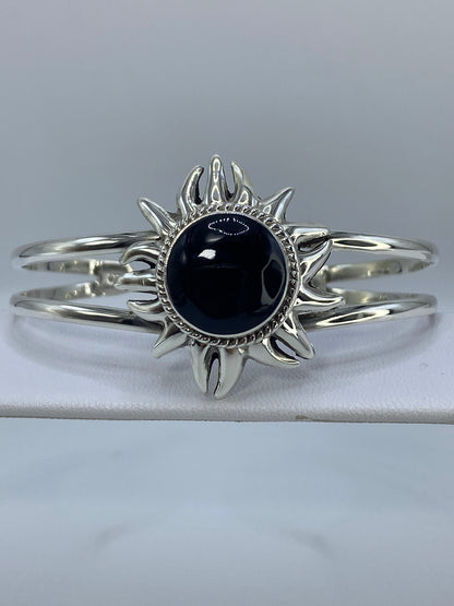 Brazalete de plata 925 rígido con ónix negro engastado, vista frontal mostrando el diseño de sol