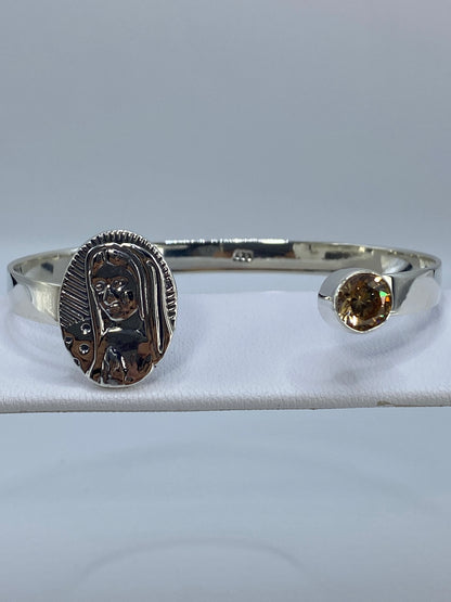 Brazalete de plata rígido con circonia café en la muñeca de una mujer