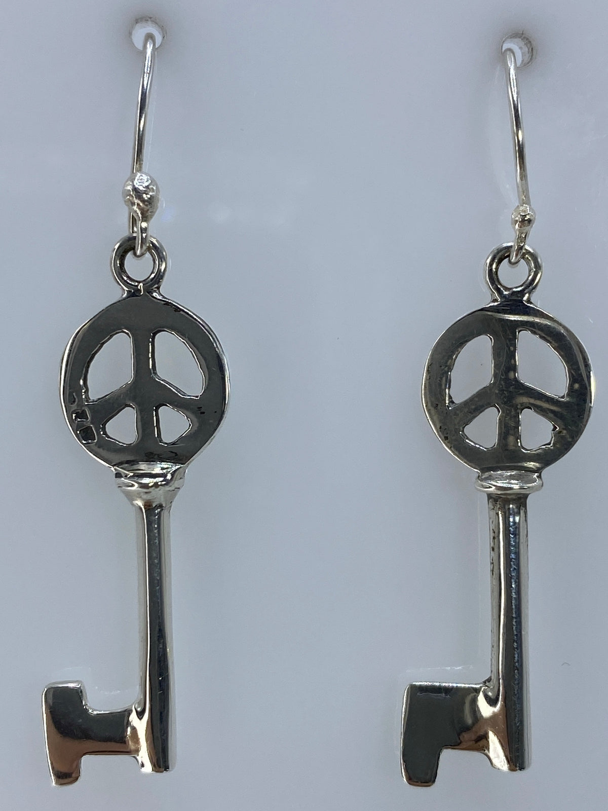 Aretes de plata paz sobre escala con medida de 4 cm de largo