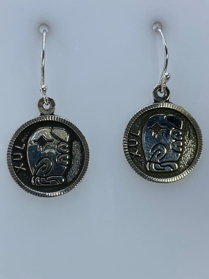 Par de aretes de plata con motivo prehispánico Xul repujado, en par colgando de ganchos de plata