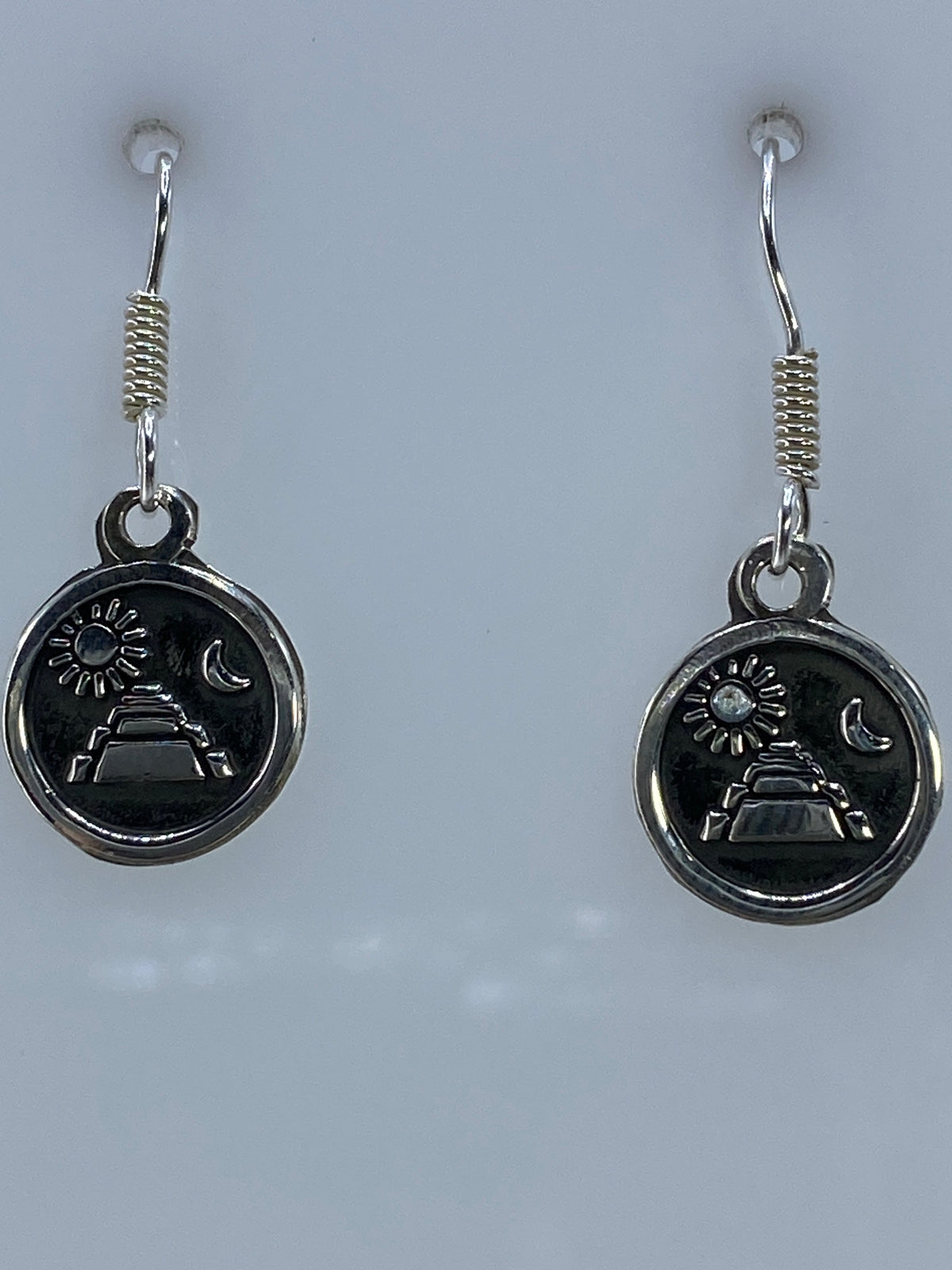 Aretes prehispánicos de plata sobre regla mostrando largo de 2.4 cm