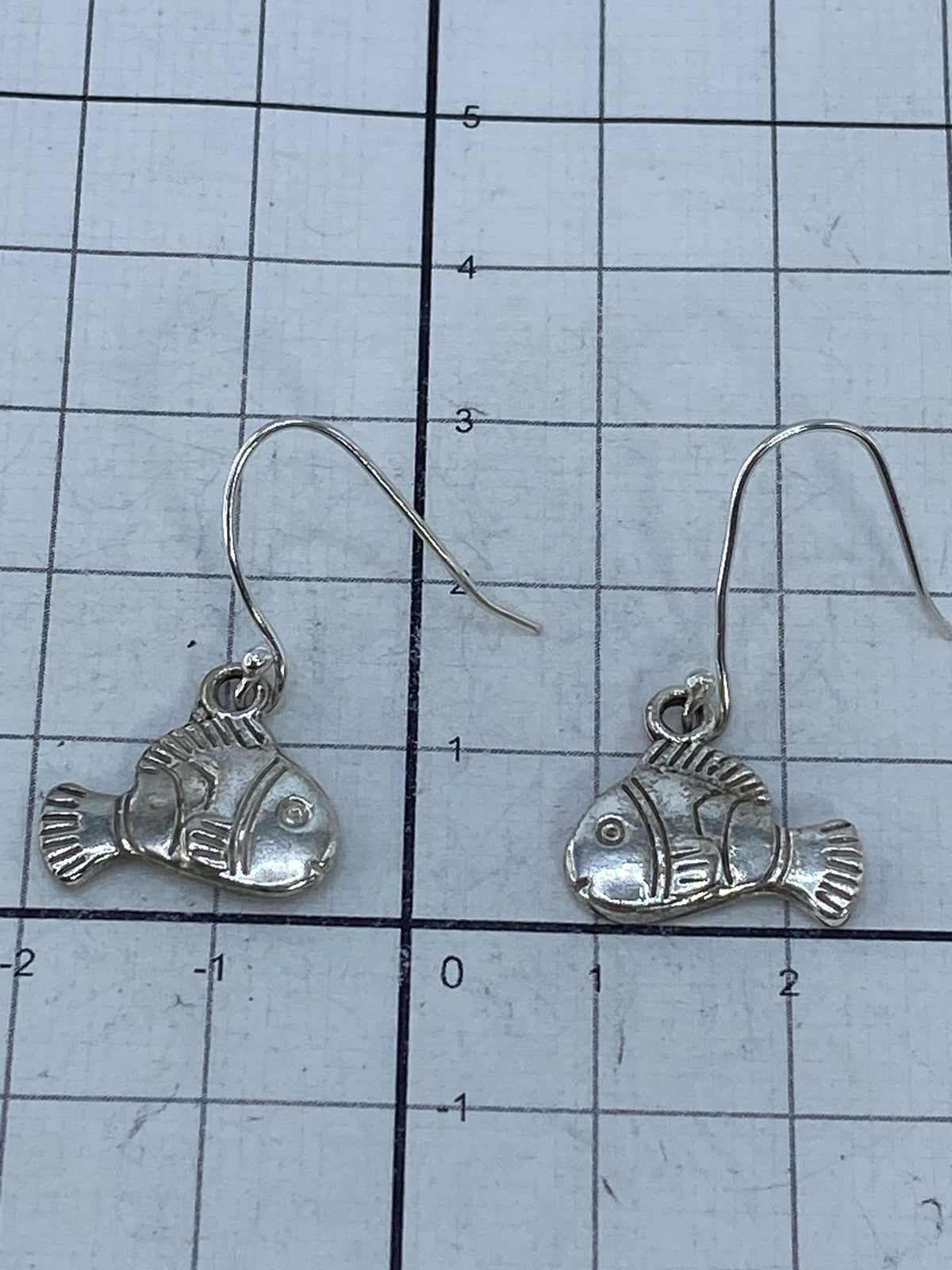Aretes pececillo en la mano, mostrando escala real de 3 cm y el acabado de plata 925