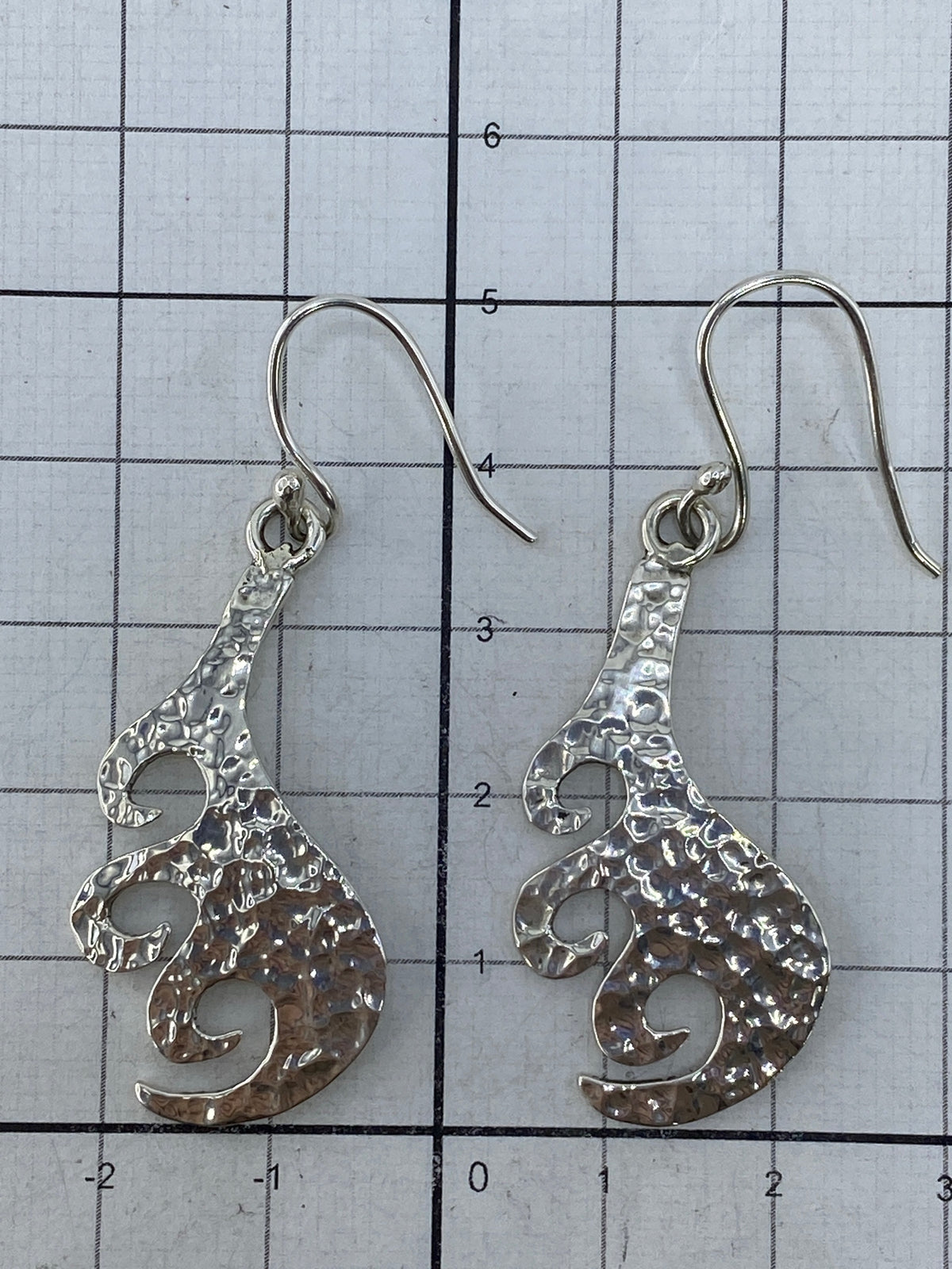 Aretes colocados sobre plano plata mostrando simetría y acabado pulido
