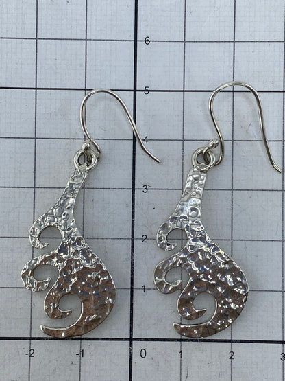 Aretes colocados sobre plano plata mostrando simetría y acabado pulido