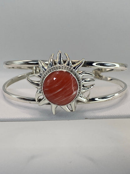 Brazalete puesto en muñeca de mujer, piedra rosa brillando en contraste con plata