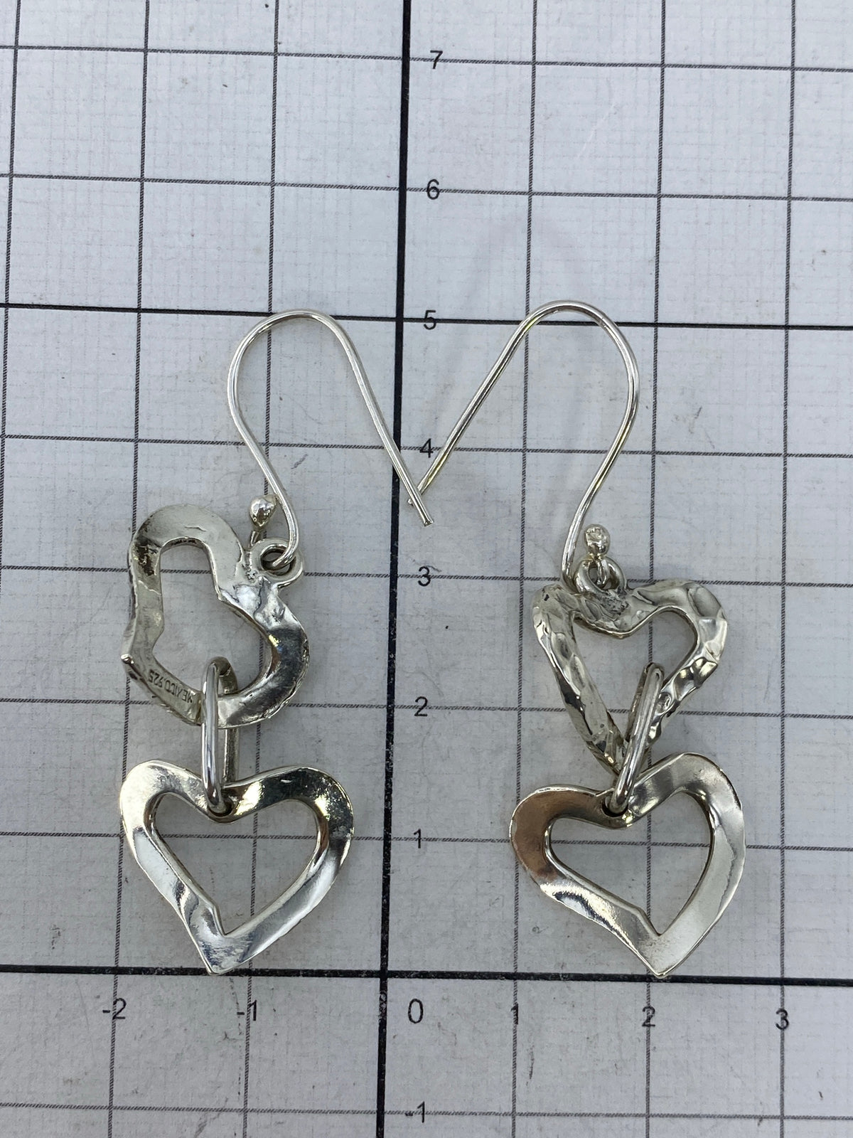 Los aretes colgando delicadamente — diseño de corazones conectados en movimiento