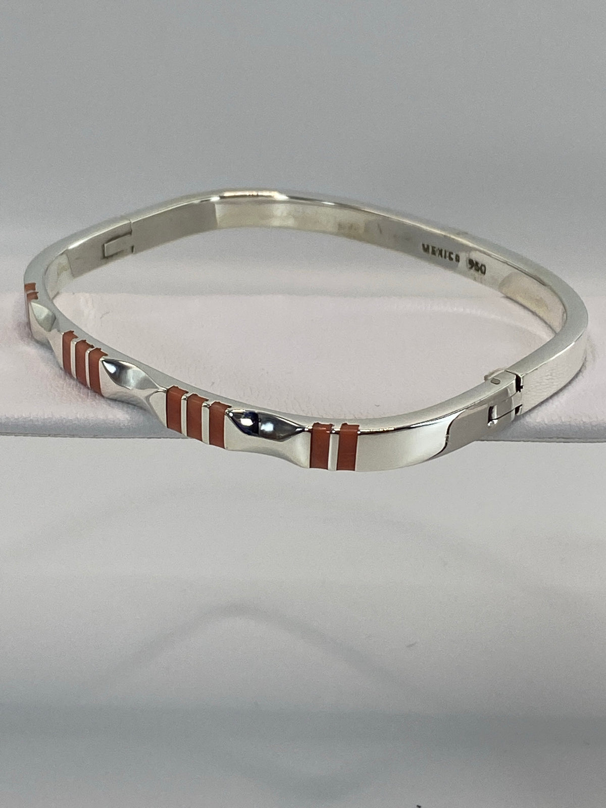Brazalete de plata puesto en la muñeca, mostrando el ancho de banda y el coral rosa