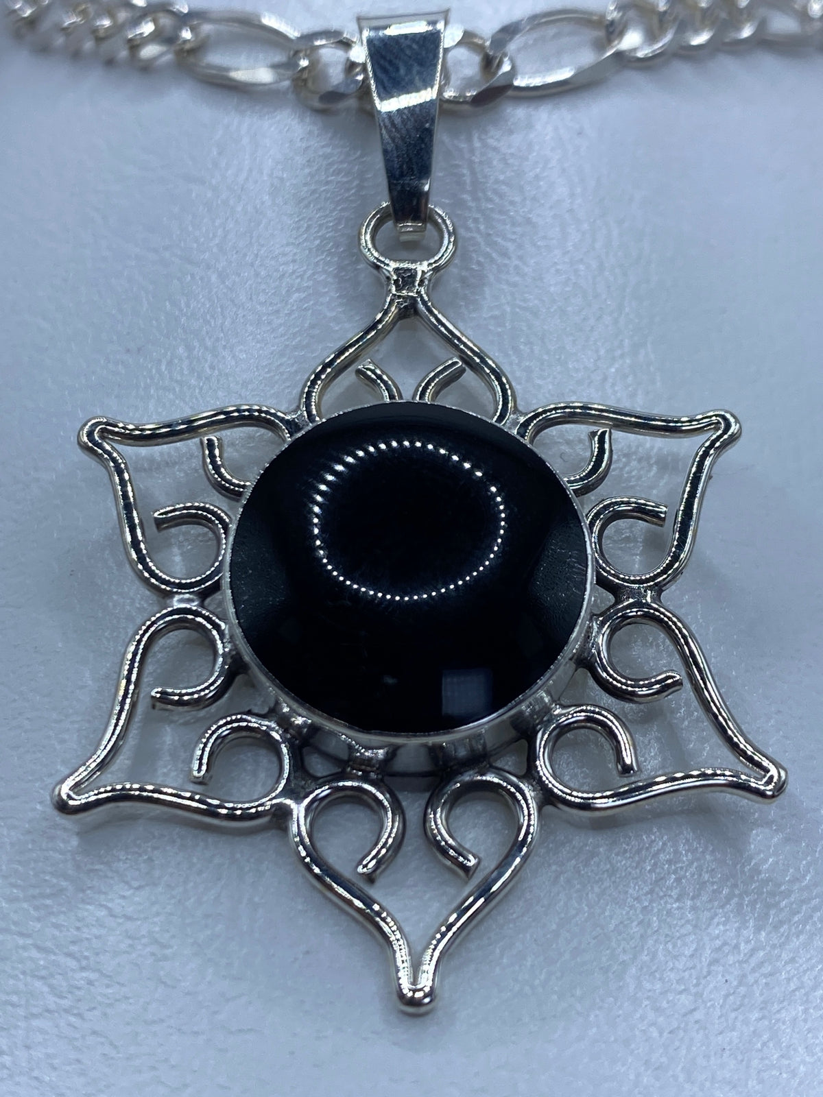 Vista frontal del dije mandala ónix negro 5.1 cm sobre cadena de eslabones plateados