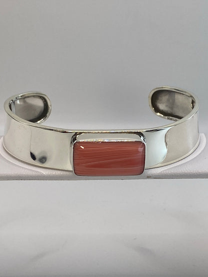 Brazalete de plata rígido con coral roja engastada en el centro, vista frontal