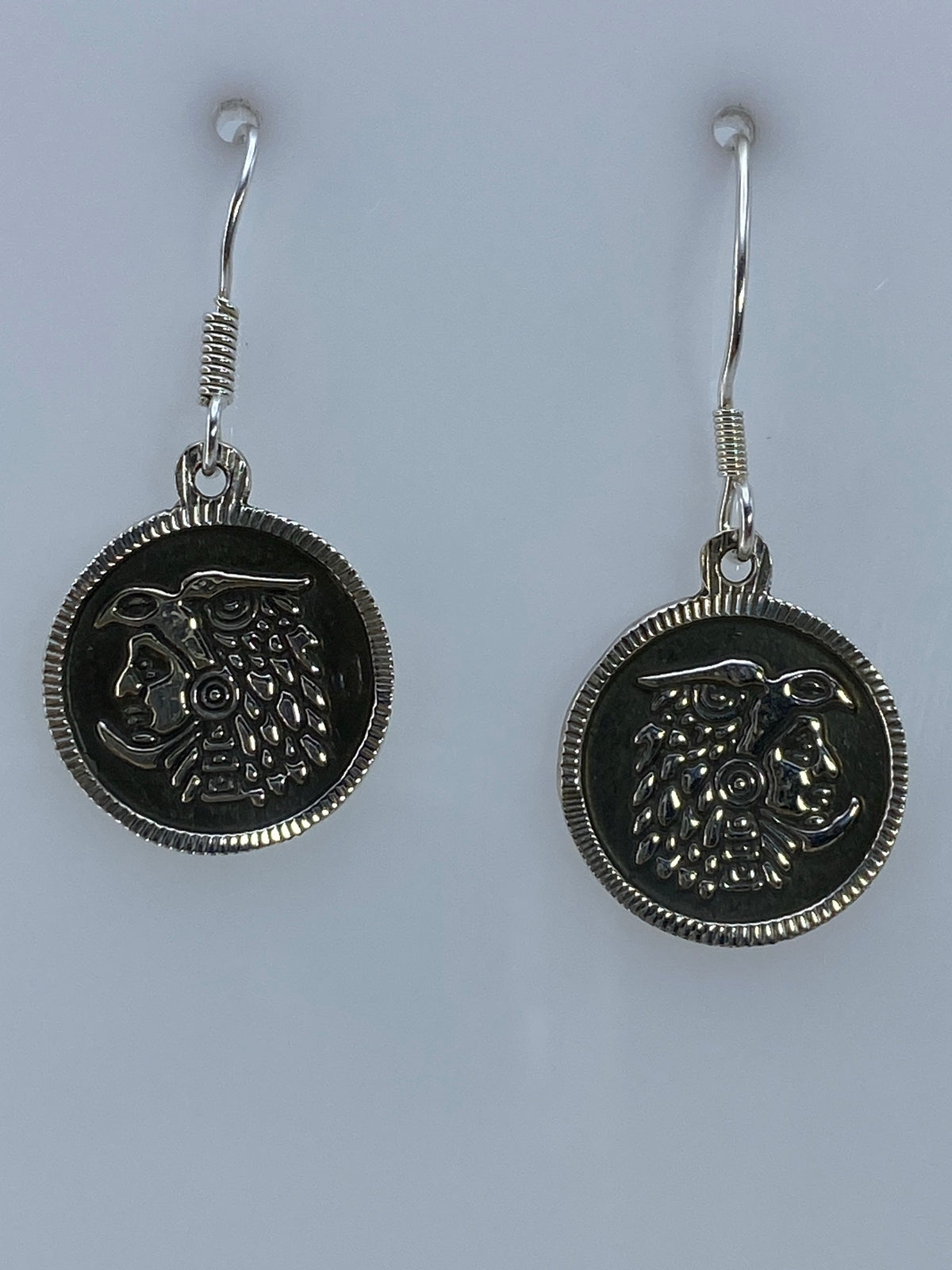 Par de aretes de plata en repujado con rostro prehispánico, vista frontal