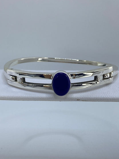 Brazalete rígido de plata con lapislázuli azul en forma de media luna sobre fondo gris