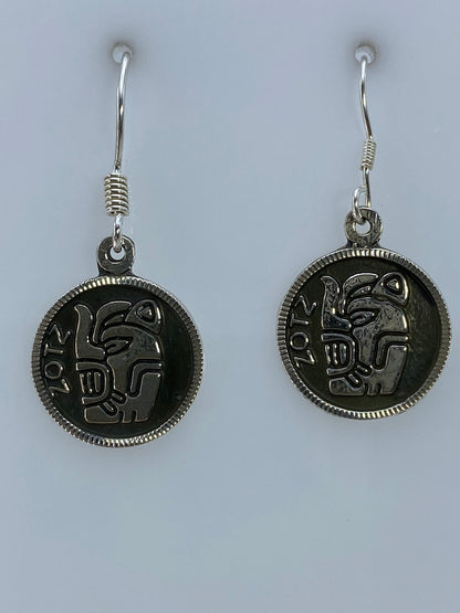 Par de aretes de plata repujado con motivo prehispánico azteca colgando