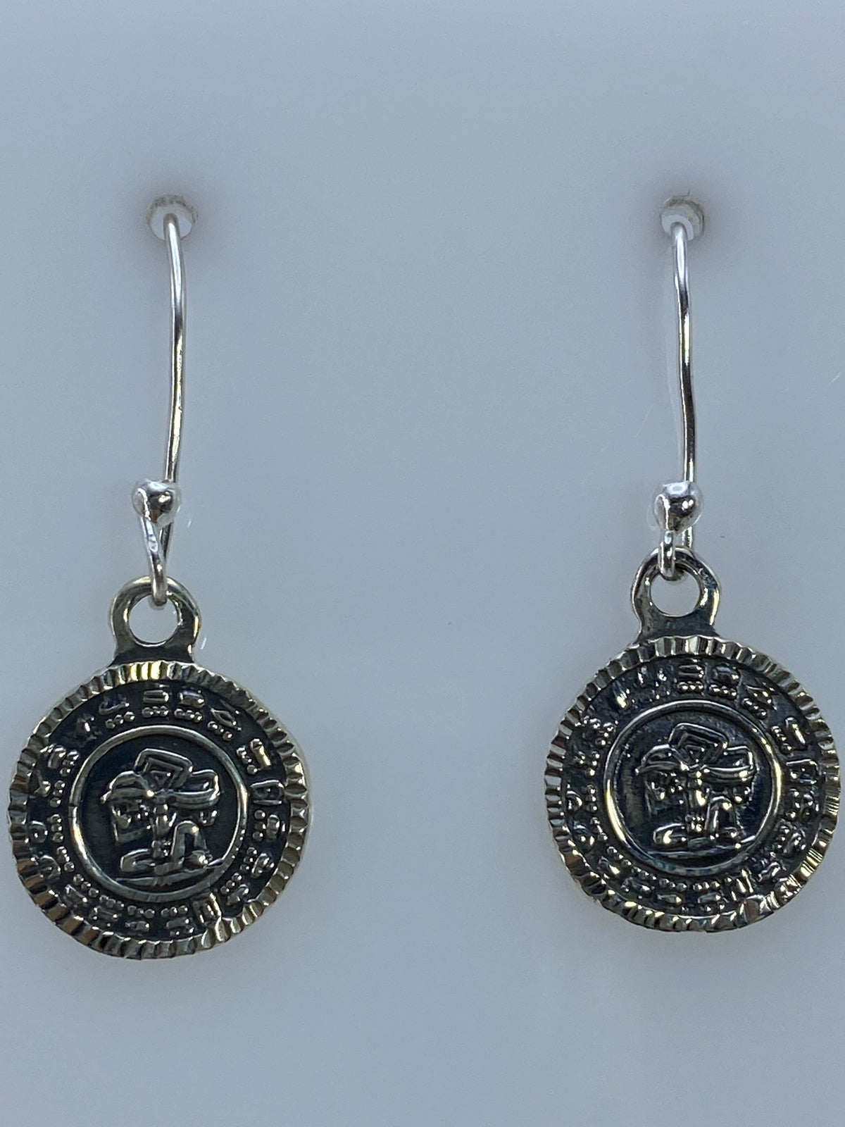 Aretes colgando en gancho de plata, vista lateral del motivo prehispánico