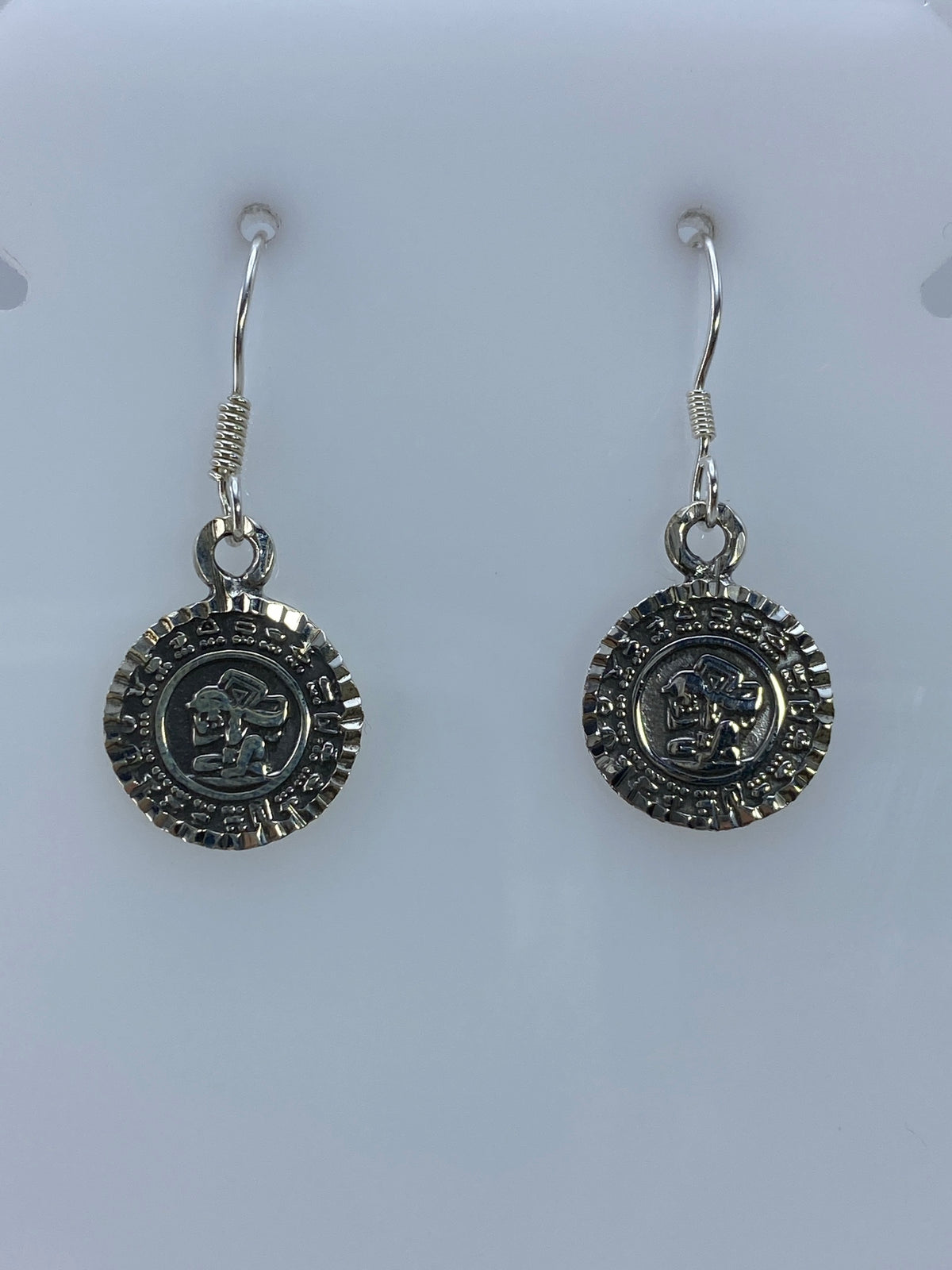 Detalle frontal de los aretes prehispánicos mostrando el relieve martillado del Calendario Azteca