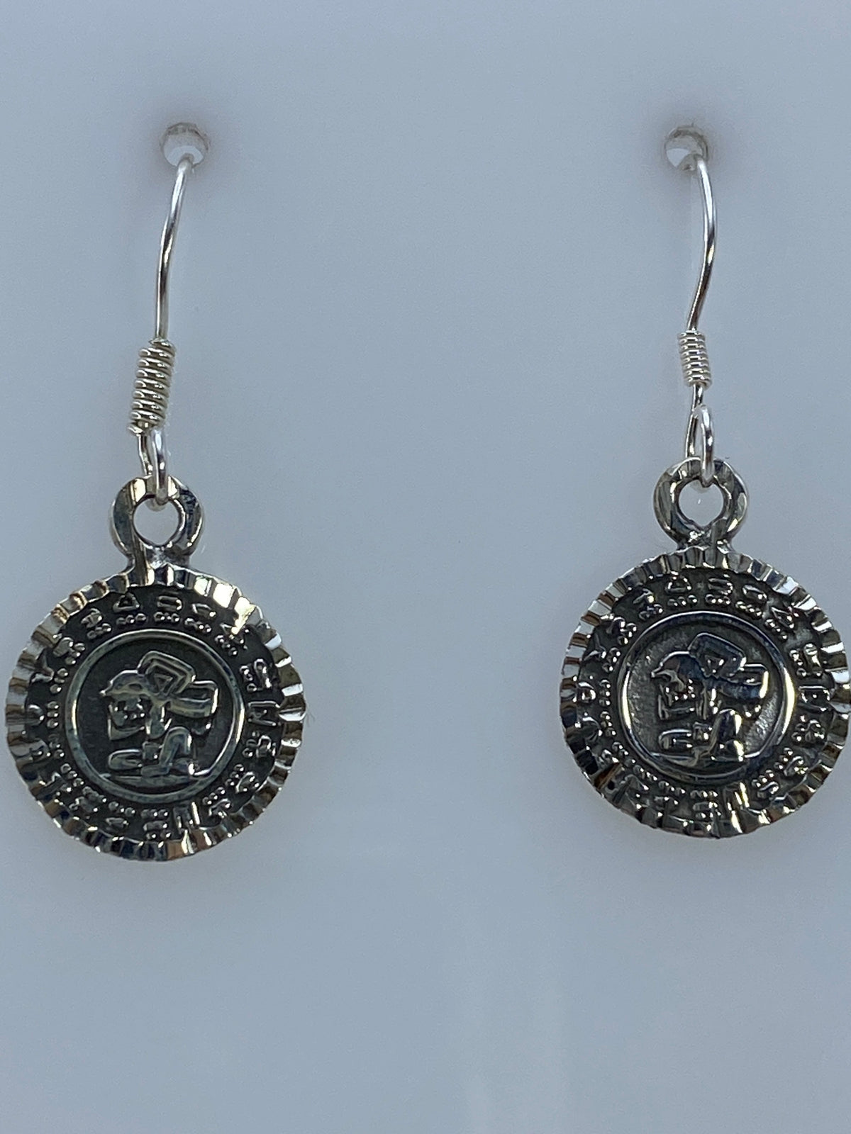 Vista lateral de los aretes de plata 950 con acabado espejo y Quinto de México