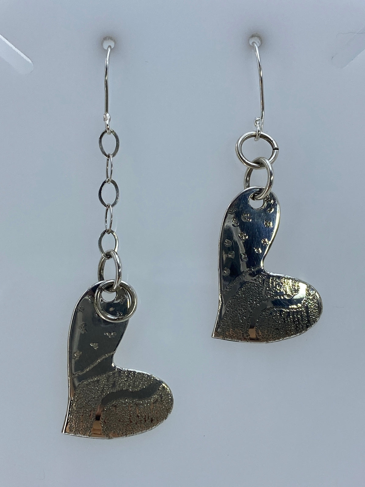 Par de aretes de plata con forma de corazón en repujado, textura martillada visible