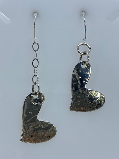 Par de aretes de plata con forma de corazón en repujado, textura martillada visible