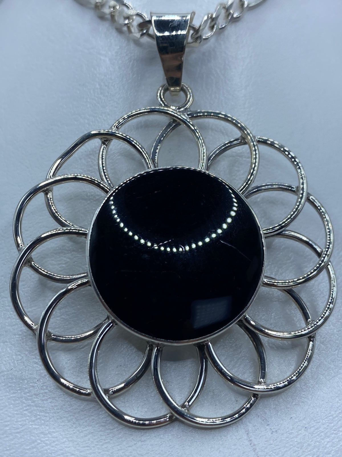 Dije de plata con ónix negro pulido, diseño floral concéntrico, de frente