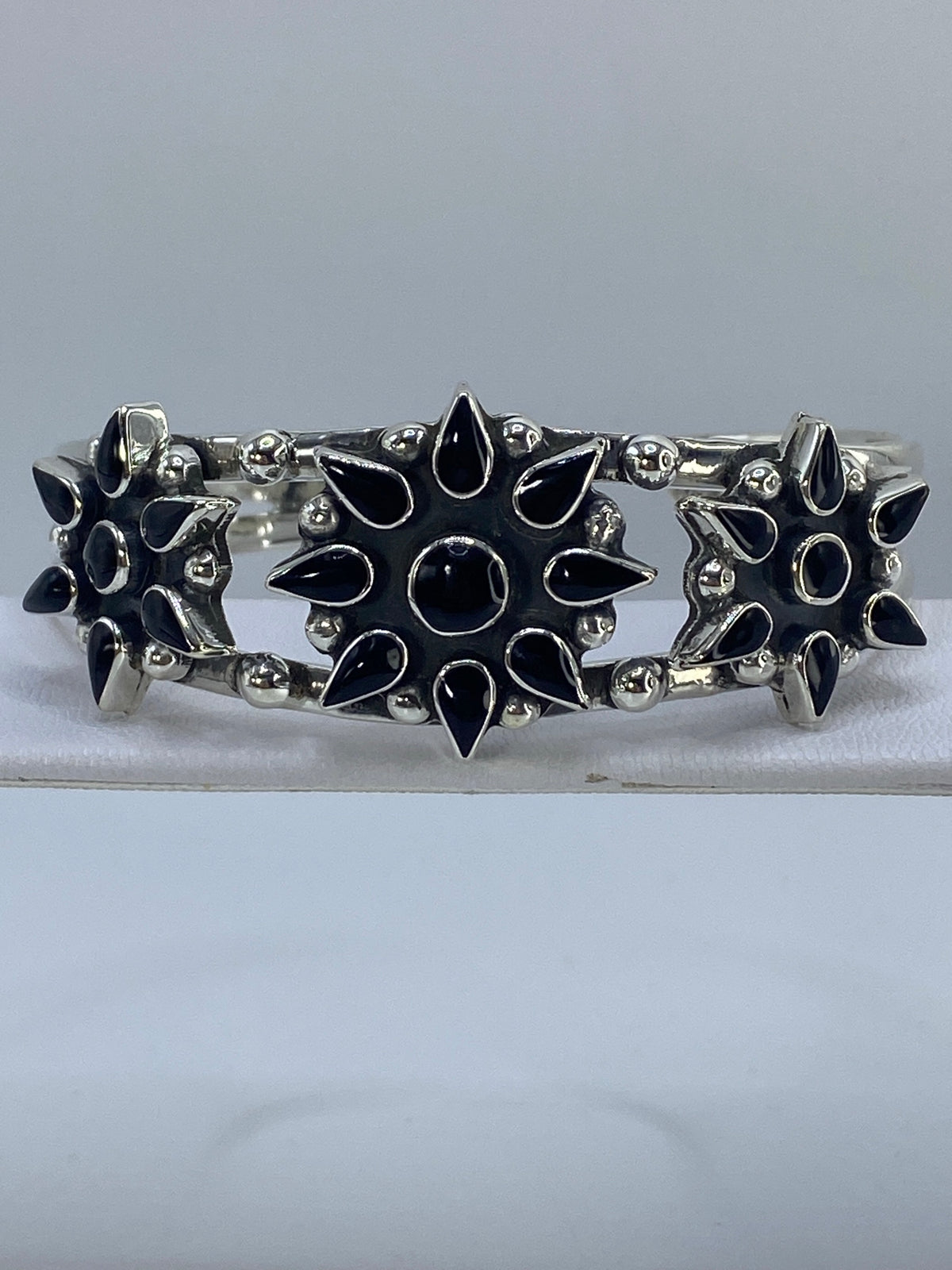 Brazalete rígido de plata con ónix negro engastada, vista frontal sobre fondo blanco