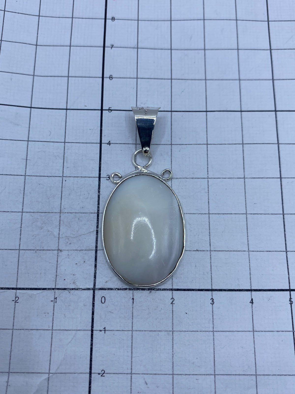 Dije de plata con perla en escala de peso sobre balanza, mostrando 5.8 gramos