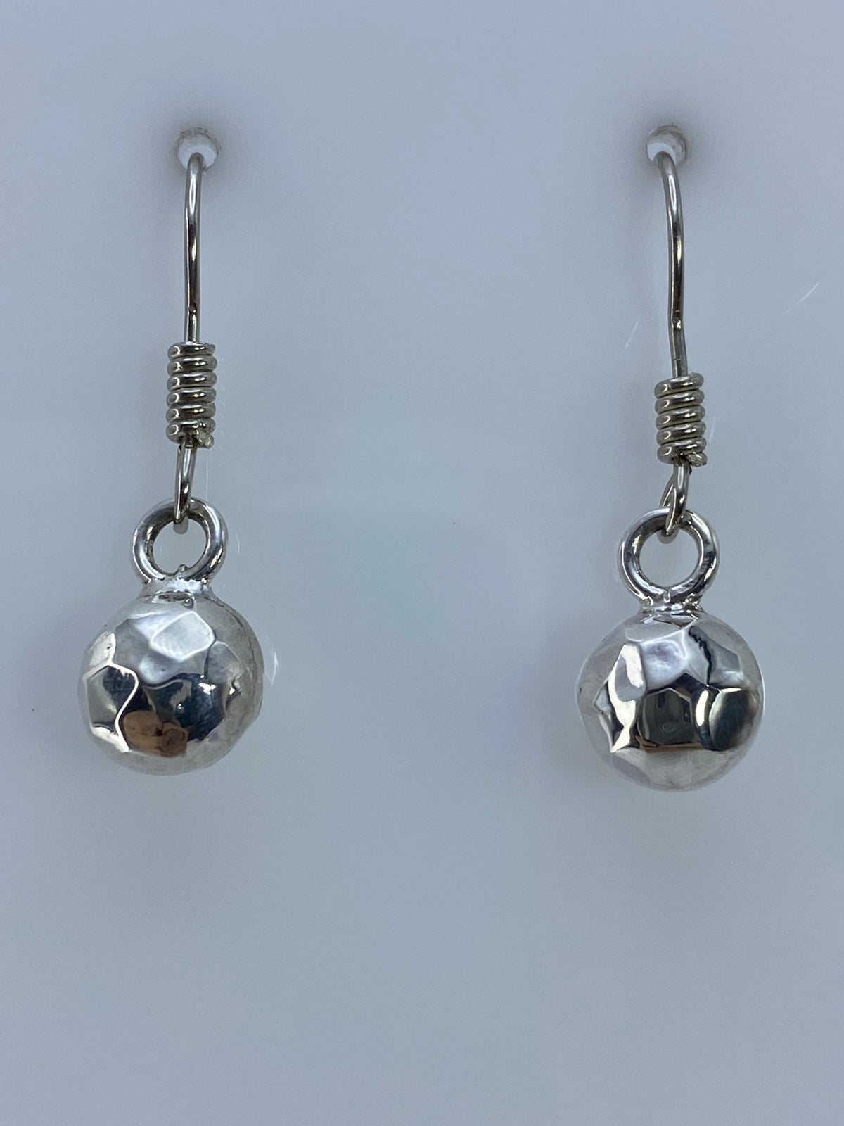 Detalle frontal de los aretes mostrando las esferas simétricas y acabado espejo