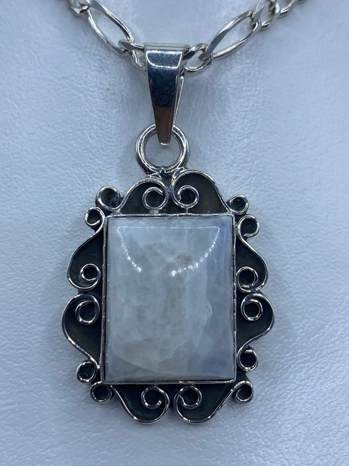 Dije rectangular de plata con cuarzo iridiscente engastado, marco ornamental calado con espirales