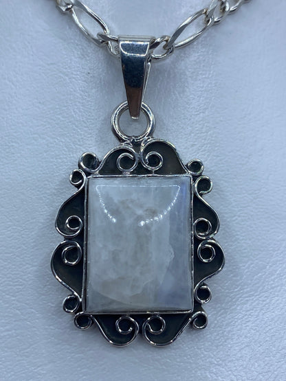 Dije rectangular de plata con cuarzo iridiscente engastado, marco ornamental calado con espirales