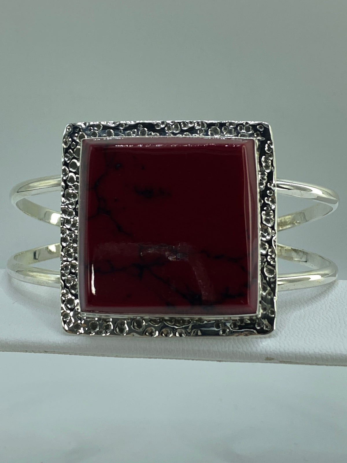 Brazalete de plata con coral rojo en muñeca de mujer, vista frontal