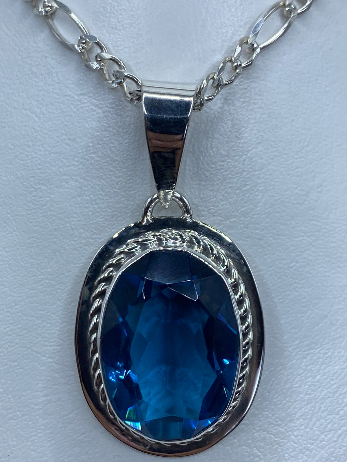 Detalle frontal del dije mostrando la circonia azul brillante y el engaste a mano