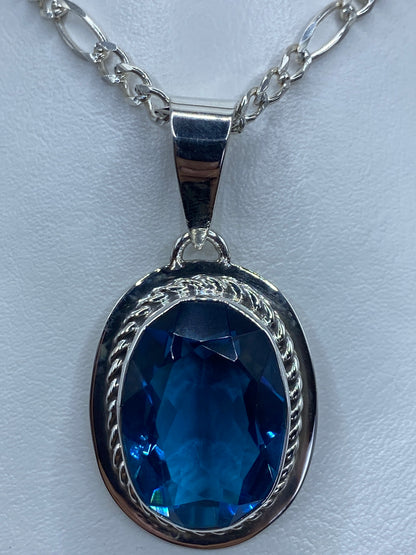 Detalle frontal del dije mostrando la circonia azul brillante y el engaste a mano