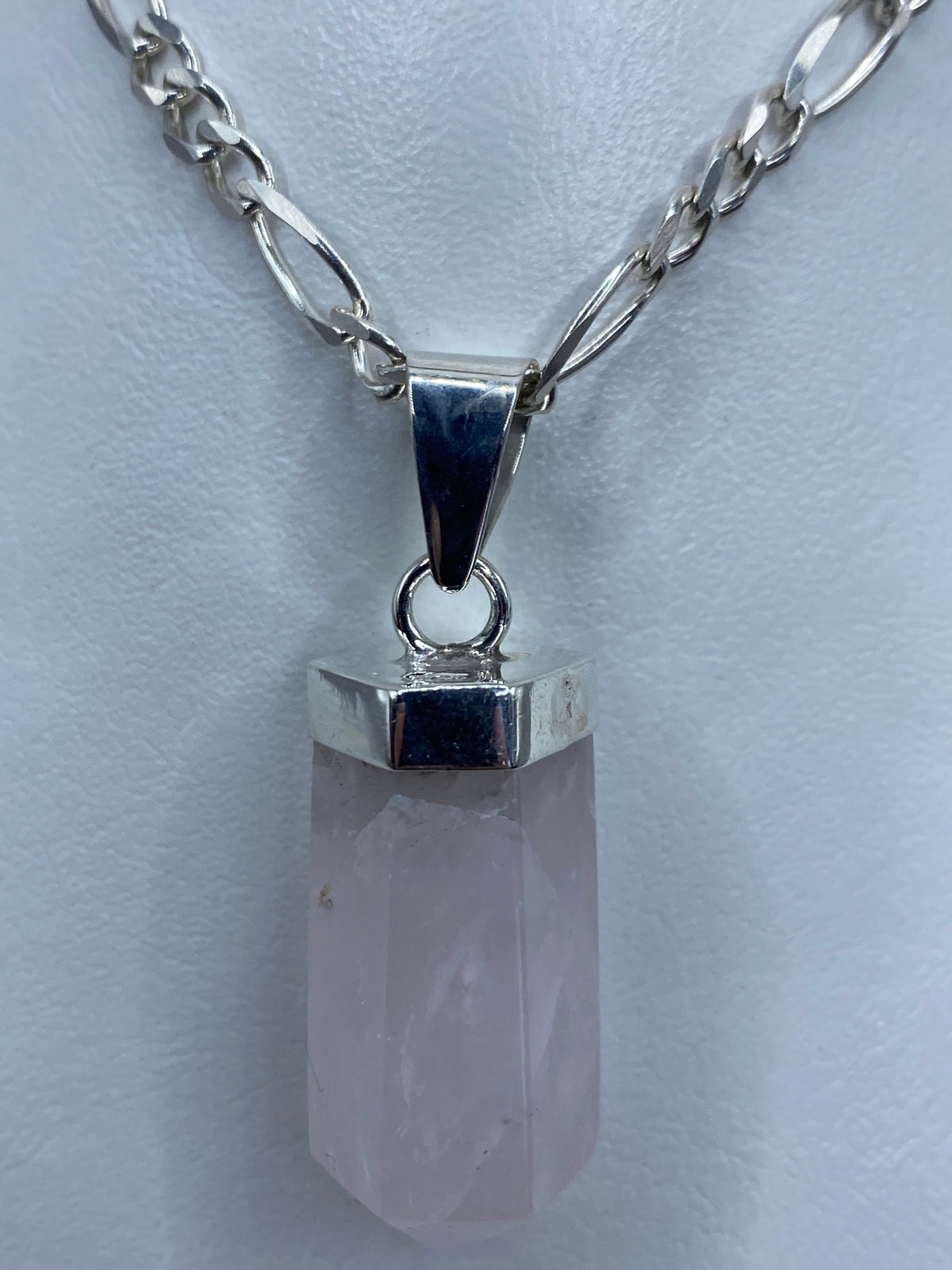 Vista frontal del dije prismático de cuarzo rosa de 4.6 cm con engaste de plata